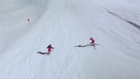 Drone-view-of-skiers-going-down-a-slope-in-the-Pyrenees,-Spain,-learning-to-ski
