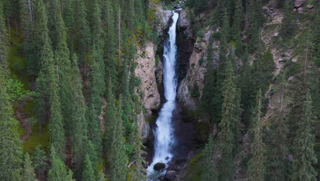 Aerial-shot-Barskoon-Waterfall-in-Fairy-Tale-Canyon-in-Kyrgyzstan,-rising-and-tilting-downward-drone-shot
