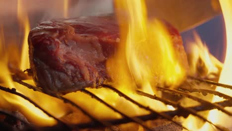 Ein-Koch-Dreht-Ein-Gegrilltes-Steak-Inmitten-Von-Flammen,-Rauch-Und-Grillkohle