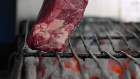 A-cook-places-a-steak-on-a-barbecue-with-coals