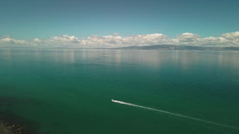 Boat-gliding-across-glass-lake-in-summer