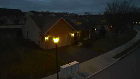 Aerial-orbit-around-street-light-revealing-small-American-home-at-night