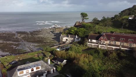 Aerial-drone-orbit-shot-of-an-English-mill-house-on-the-shoreline-of-a-coastal-village---Lee-Bay,-Beach,-Ilfracombe,-Devon,-England