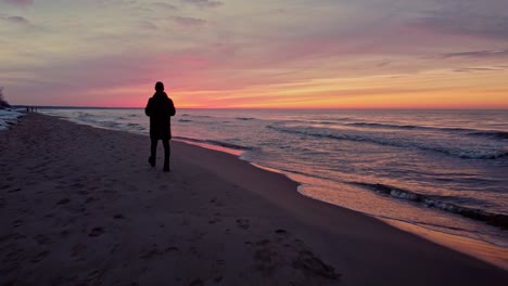 Silhouette-Einer-Person-Am-Strand-Mit-Einem-Farbenfrohen-Sonnenuntergang-Am-Horizont