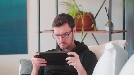 Young-hipster-man-playing-video-games-on-handheld-console