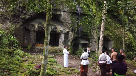 Balinese-Priestess-Guides-Religious-Ceremony-at-Goa-Garba-Bali-Temple-Stone-Cave-with-Ancient-Archaeological-Architecture,-Indonesian-Hindu-Tradition