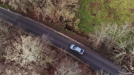 Top-Down-Aerial-View-of-Car-Driving-on-Street-in-Moody-Landscape