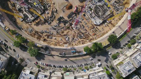 An-aerial-view-of-a-tower-crane-on-a-construction-site-in-a-big-city-square-as-it-rotates-around-it---top-down-shot