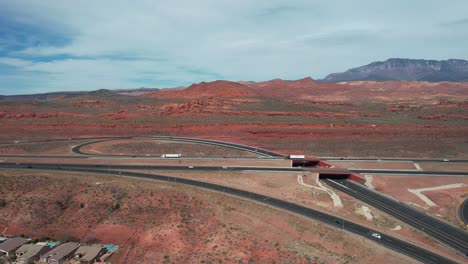 Traffic-on-American-I-15-Highway-and-Church-Rocks-Red-Sandstone-Formations-by-Hurricane-Utah-USA,-Drone-Aerial-View