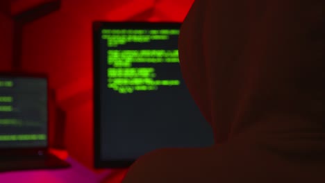 Anonymous-hacker-writing-code-in-a-red-room