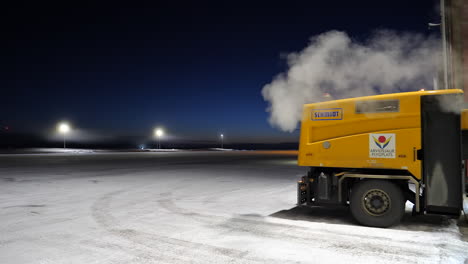 Snow-Removal-Truck-Exiting-Hangar-at-Winter-Arctic-Airport,-Arvidsjaur