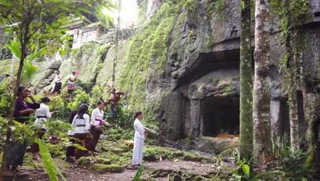 Balinese-People-Praying-at-Goa-Garba-Temple,-Ancient-Stone-Archaeological-Cave,-wearing-Traditional-Clothes,-Sarong-from-Bali-Hindu-Culture,-Tampaksiring,-Gianyar