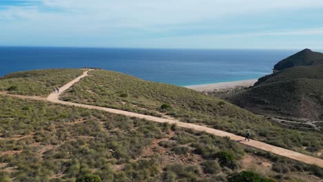 Woman-walks-to-Los-Muertos-Beach-in-Cabo-de-Gata,-Andalusia,-Spain---Aerial-4k