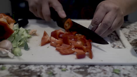 Close-Up-View-Of-Cook-Cutting-Red-Peppers-On-Kitchen-Board