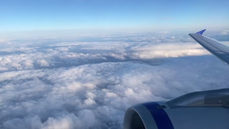 Vista-Desde-La-Ventana-De-Un-Avión-Alto-Sobre-Las-Nubes-Con-Cielo-Azul