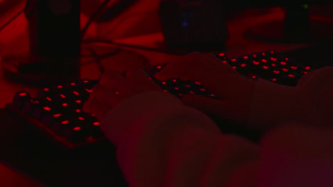 Anonymer-Hacker-In-Einem-Dunkelroten-Raum,-Der-Auf-Einer-Roten-Tastatur-Tippt