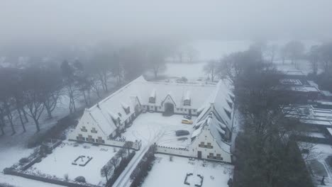 Aerial-orbit-of-beautiful-old-farmhouse-in-a-snow-covered-rural-landscape