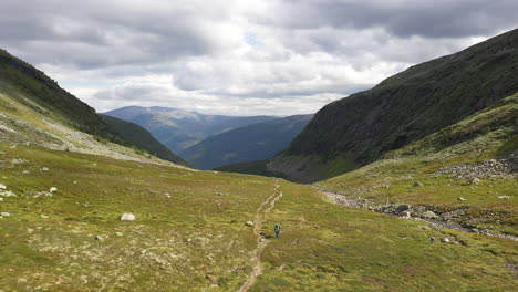 Person,-Die-Ein-Wunderschönes-Grünes-Tal-In-Den-Bergen-In-Norwegen-Hinunterwandert