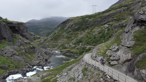 Person-cycling-down-a-scenic-part-of-the-famous-Rallarvegen,-the-hiking-and-cycling-road-between-the-mountains-in-Finse-and-the-fjord-in-Flåm,-Norway