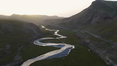 Epic-cinematic-revealing-drone-shot-of-a-river-leading-into-the-Kel-Suu-lake-during-golden-hour-in-Kyrgyzstan