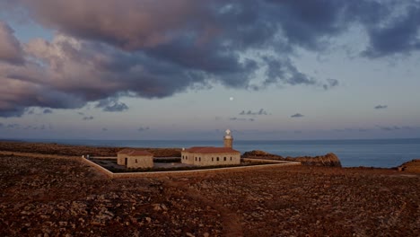 Aerial-reveal-of-Punta-Nati-Lighthouse-in-Menorca-Spain-at-sunset