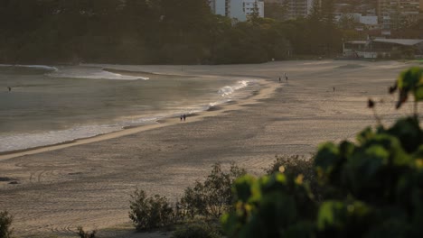 View-across-Coolangatta-from-Kirra-Hill-with-people-walking-on-the-beach-at-sunrise,-Gold-Coast,-Australia