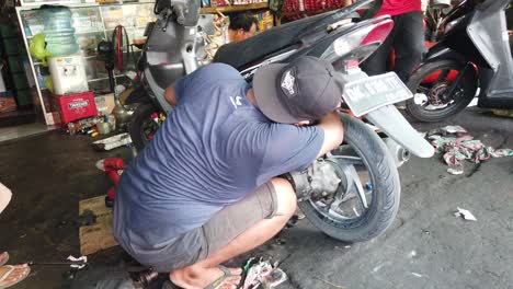 Motorcycle-Mechanic-Fixing-The-Back-Suspension-of-an-Honda-Vario-Scooter-in-Bali,-Indonesia,-Southeast-Asia