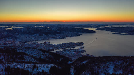 Hermosa-Toma-Aérea-Que-Revela-La-Ciudad-Y-El-Puerto-En-Bergen,-Noruega-Durante-La-Hora-Azul-Con-Un-Hermoso-Cielo-Naranja-Después-Del-Atardecer