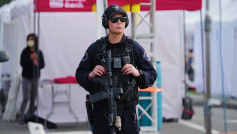 A-Police-Officer-with-an-Assault-Rifle-Stands-Guard-Outside-Vendor-Tents-After-the-Monterey-Park-Shooting-during-Lunar-New-Year