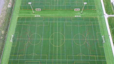 Sports-grounds-with-soccer-fields,-high-angle-drone-reveal-shot