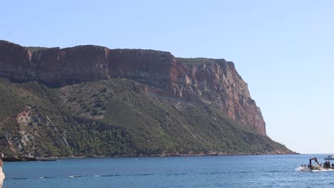 Boat-passing-by-mountain-in-southern-France,-Cassis