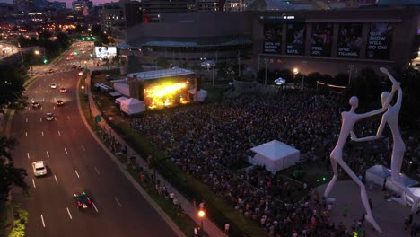 Drone-flight-over-Speer-Boulevard-and-crowd-at-night-concert---Sculpture-Park,-Performing-Arts-Complex,-downtown-Denver,-Colorado