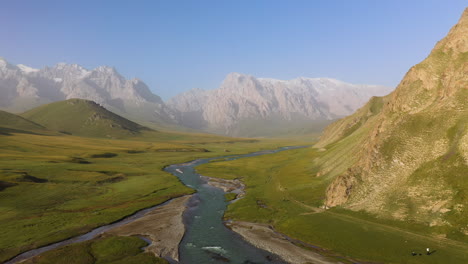 Epic-rotating-aerial-drone-shot-of-a-small-river-beside-a-mountain-near-the-Kel-Suu-lake-in-Kyrgyzstan