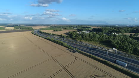 Establishing-Drone-Shot-of-Combine-Harvester-next-to-Motorway-on-Sunny-Day-at-Golden-Hour-in-Yorkshire-UK