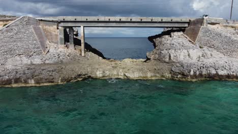 Cinematic-aerial-view-drone-shot-flying-under-glass-window-bridge-on-the-island-of-eleuthera-in-the-bahamas---separating-the-atlantic-ocean-from-the-caribbean-sea