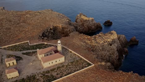Pull-back-aerial-tilt-down-of-Punta-Nati-Lighthouse-at-golden-hour