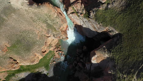 Epic-revealing-drone-shot-of-a-small-waterfall-leading-from-a-river-near-the-Kell-Suu-lake-in-Kyrgyzstan