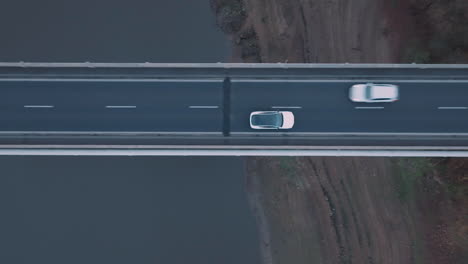 Birds-Eye-Aerial-View-of-White-Electric-Car-Moving-on-Bridge-Road,-Tracking-Drone-Shot