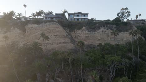 Daylight,-Sunset,-drone-footage-looking-over-cliff-with-houses-over-city