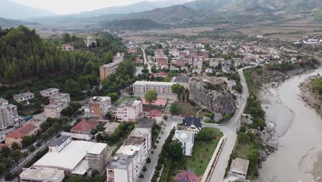 Aerial-view-of-village-in-Albania,-near-a-river-and-a-rock-climbing-site
