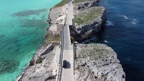 Cinematic-aerial-view-drone-shot-following-a-car-crossing-glass-window-bridge-on-the-island-of-eleuthera-in-the-bahamas---separating-the-atlantic-ocean-from-the-caribbean-sea