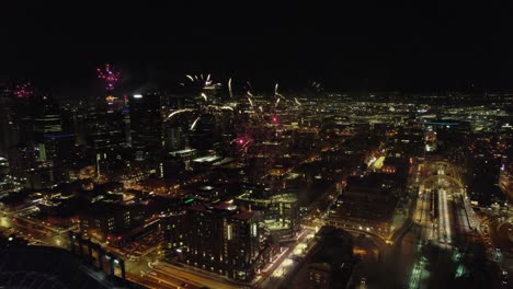 Aerial-Drone-View-Flying-Backwards-Through-Exploding-Fireworks-Show-Over-Downtown-Denver-Skyline-At-Night