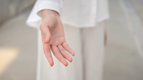Close-up-of-woman-dressed-in-white-reaching-out-her-hand,-emotional-and-mental-support-concept