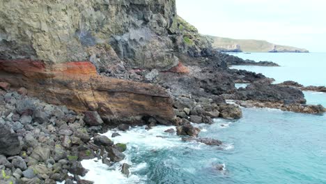 Low-aerial-above-diverse-colors-and-formations-of-volcanic-rock-at-Banks-Peninsula