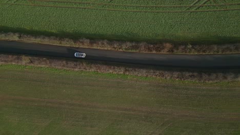 Top-down-drone-shot-of-a-white-car-in-a-uk-road