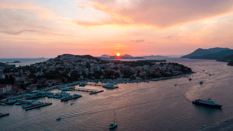 Aerial-hyperlapse-of-the-sun-setting-over-an-active-coastal-port-in-Dubrovnik,-Croatia
