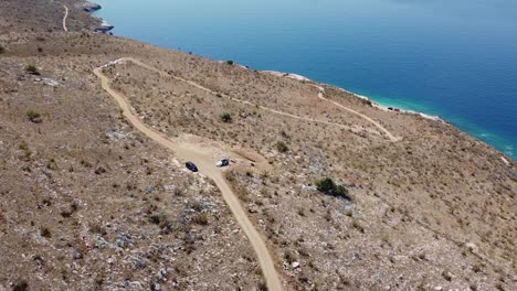 Aerial-view-of-dirt-road-access-to-beautiful-beach-in-Albania