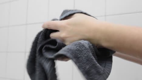 Person-is-drying-off-hands-with-a-towel-while-standing-in-a-tiled-bathroom,-hygiene-and-keeping-clean-concept