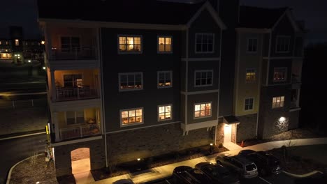Slow-aerial-pan-of-new-retirement-home-building-with-lights-on-inside-of-rooms-of-old-people