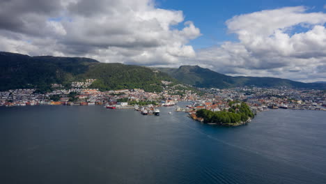 Drone-shot-over-the-bay-approaching-Bergen-and-Bryggen-on-a-sunny-day-with-beautiful-clouds